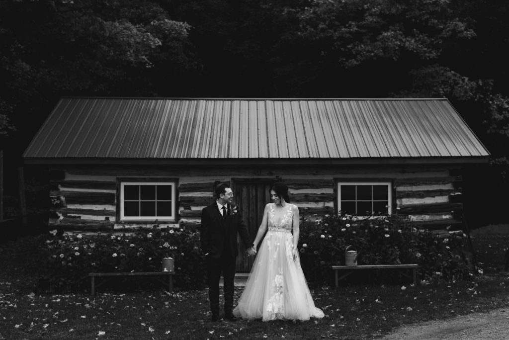 bride and groom holding hands outside wooden shed