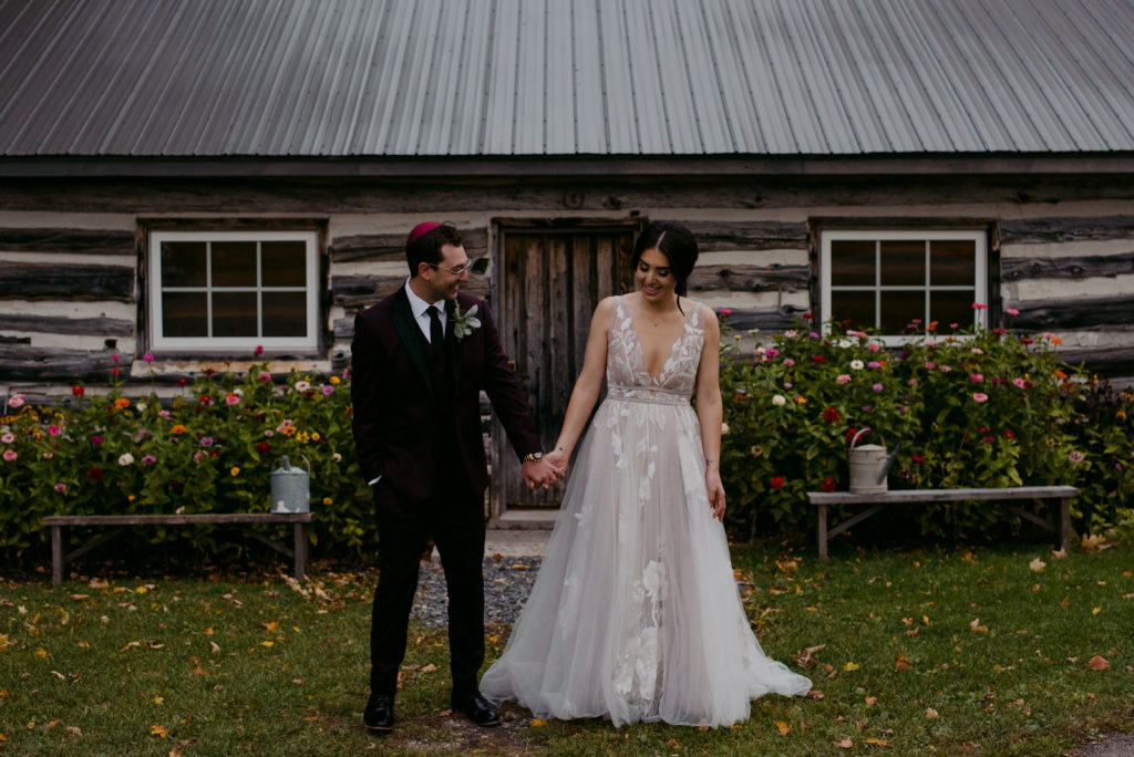 bride and groom laughing and holding hands outside wooden shed