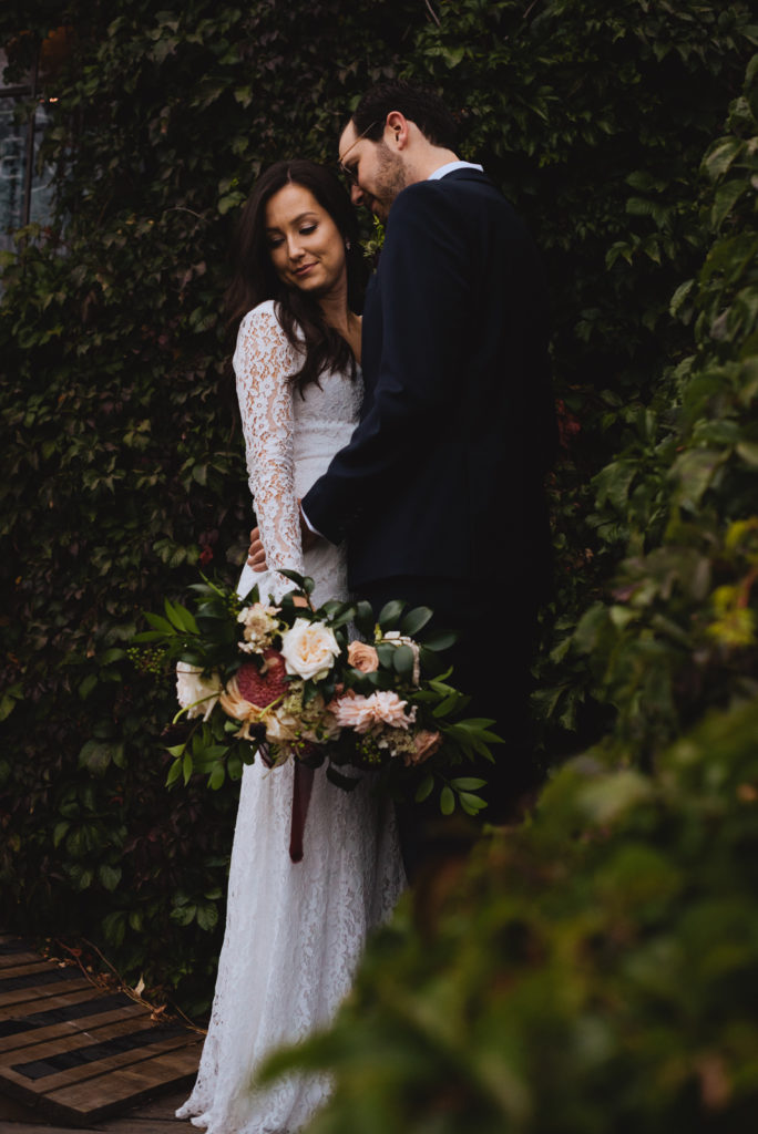 bride and groom holding wild bouquet surrounded by vines