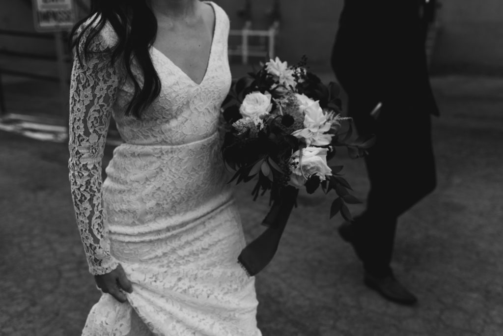 bride and groom walking through a parking lot in black and white