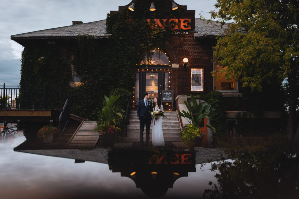 bride and groom in front of orange art gallery at dusk