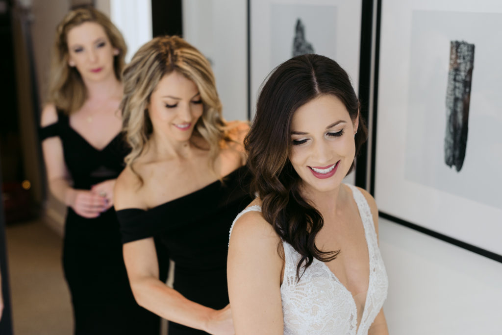 bridesmaids helping bride into her dress at the andaz hotel