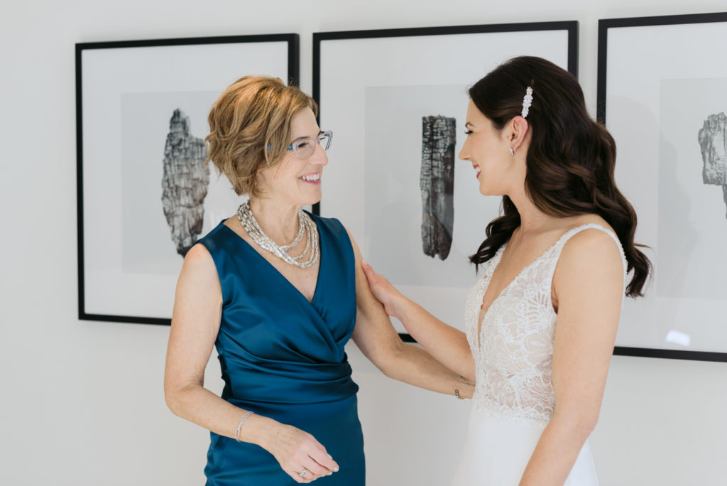 bride and mother smiling at one another as bride gets dressed at the andaz hotel