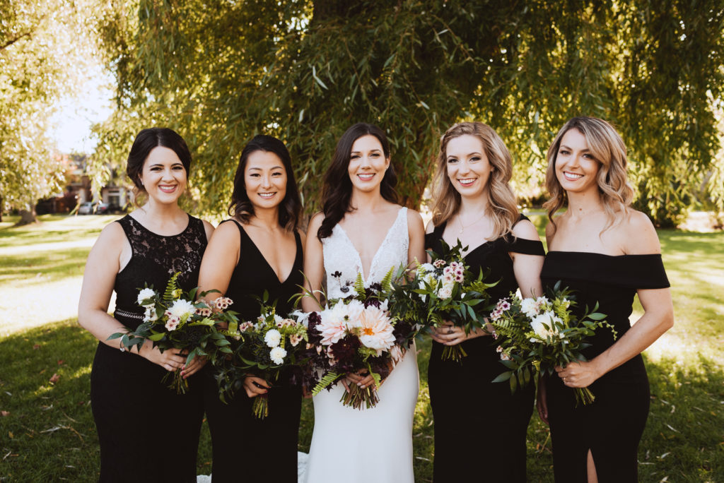 bridal party in black underneath a willow tree at sunset