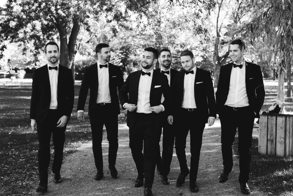 groom and groomsmen walking and laughing in a park