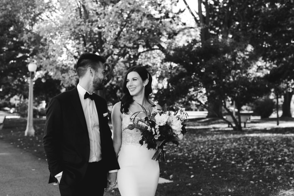 bride and groom walking in a park at sunset black and white photo