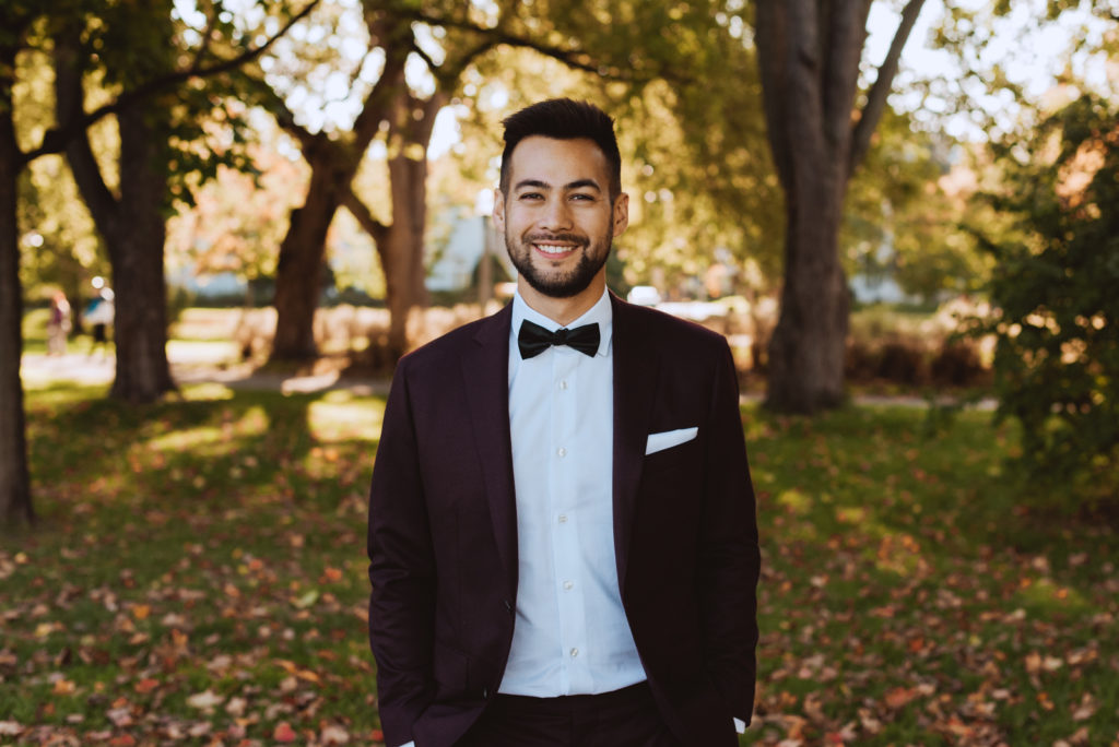 groom in a park at sunset surrounded by fall leaves