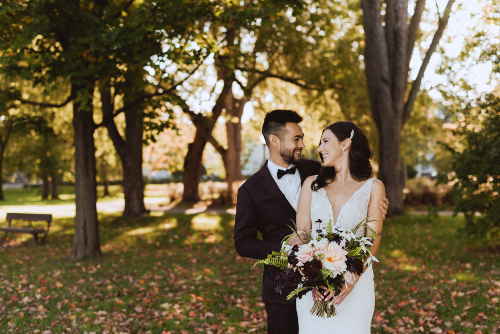 bride and groom in a park at sunset surrounded by fall leaves