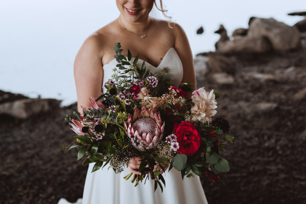 bride holding a wild bouquet underneath a bridge