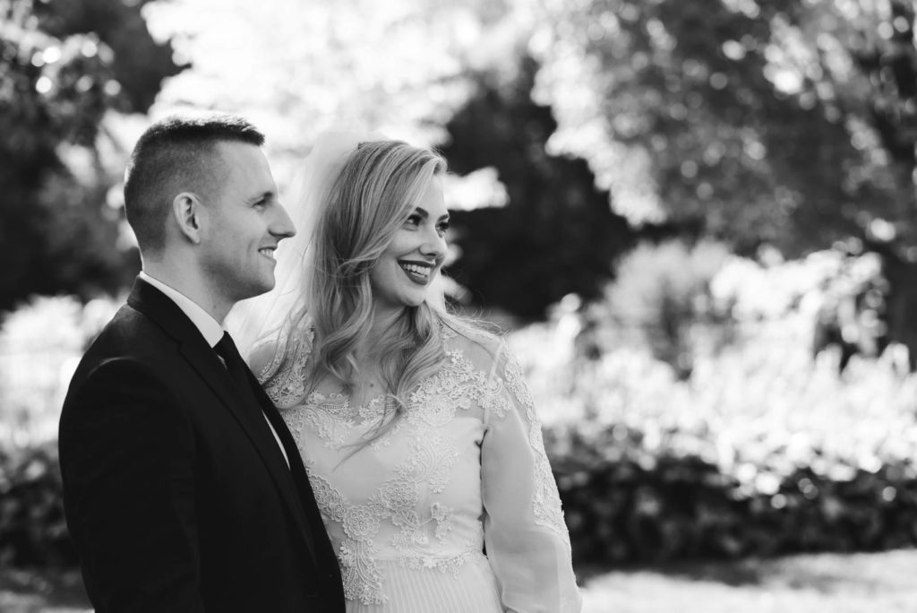 bride and groom smiling in a park in black and white