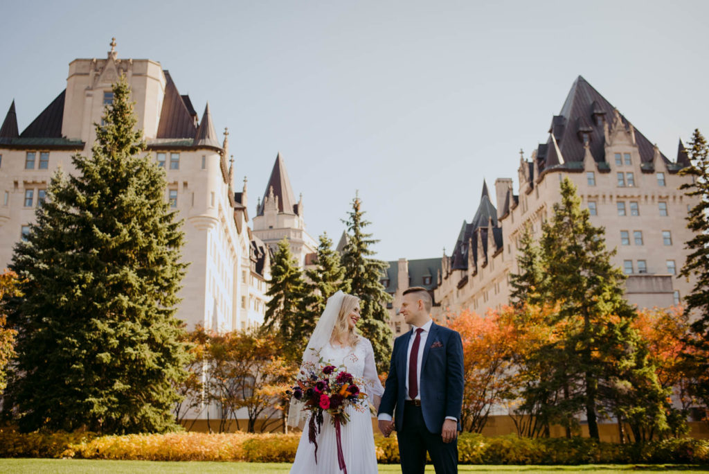 bride and groom outside the chateau laurier in majors hill park during fall wedding