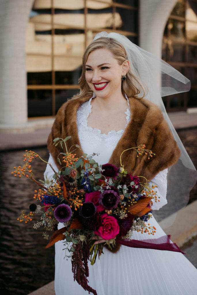 bride wearing fur shawl holding a wild bouquet