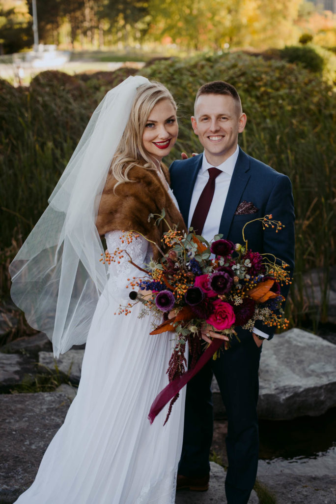bride wearing fur shawl holding a wild bouquet with her groom