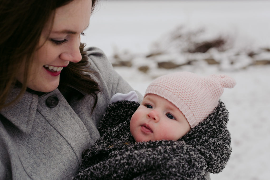 mom holding baby girl outside in winter