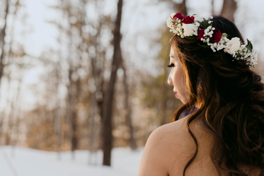 Bride with floral crown gazing into the sunset in the forest during winter