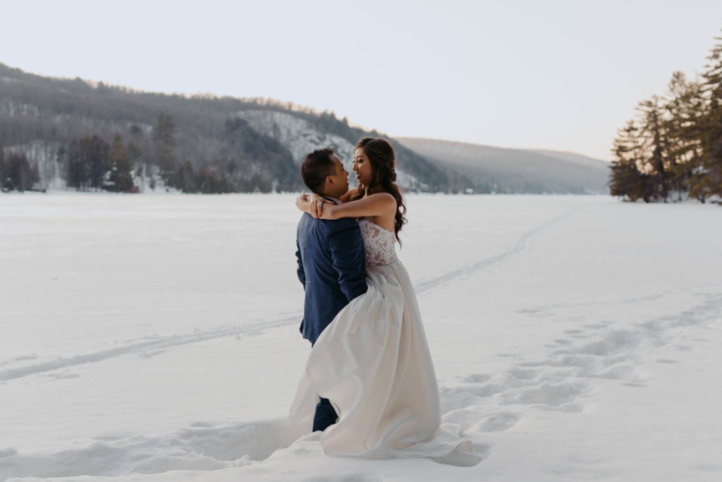 bride with legs wrapped around groom on a frozen lake at sunset