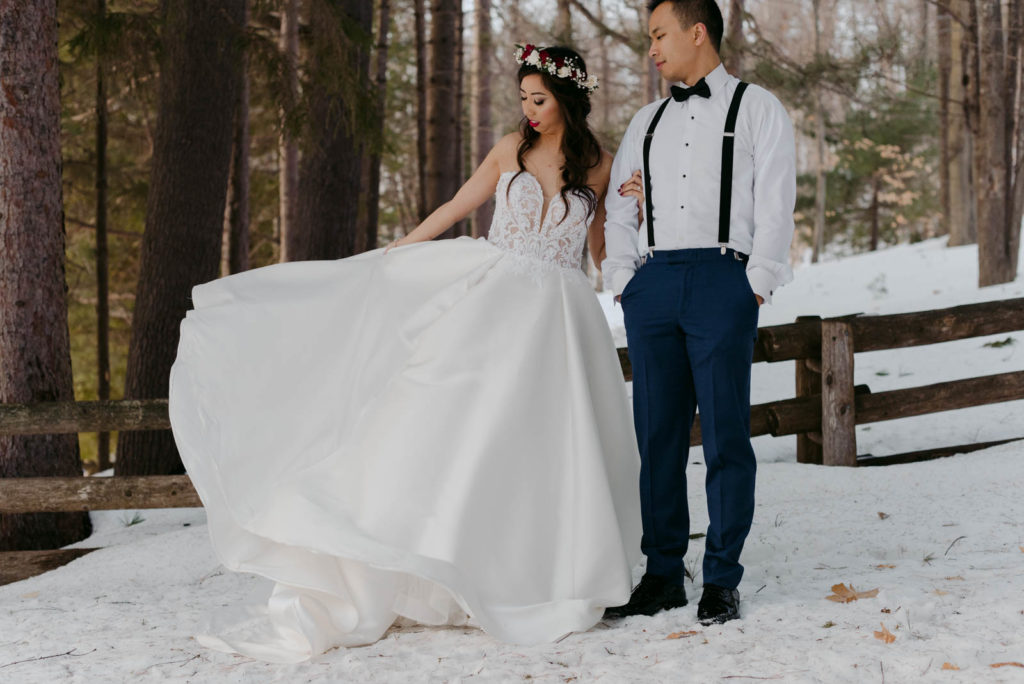bride twirling her dress in a forest in the winter
