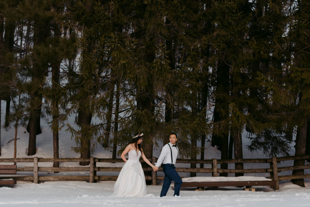 bride and groom walking through the forest in the winter