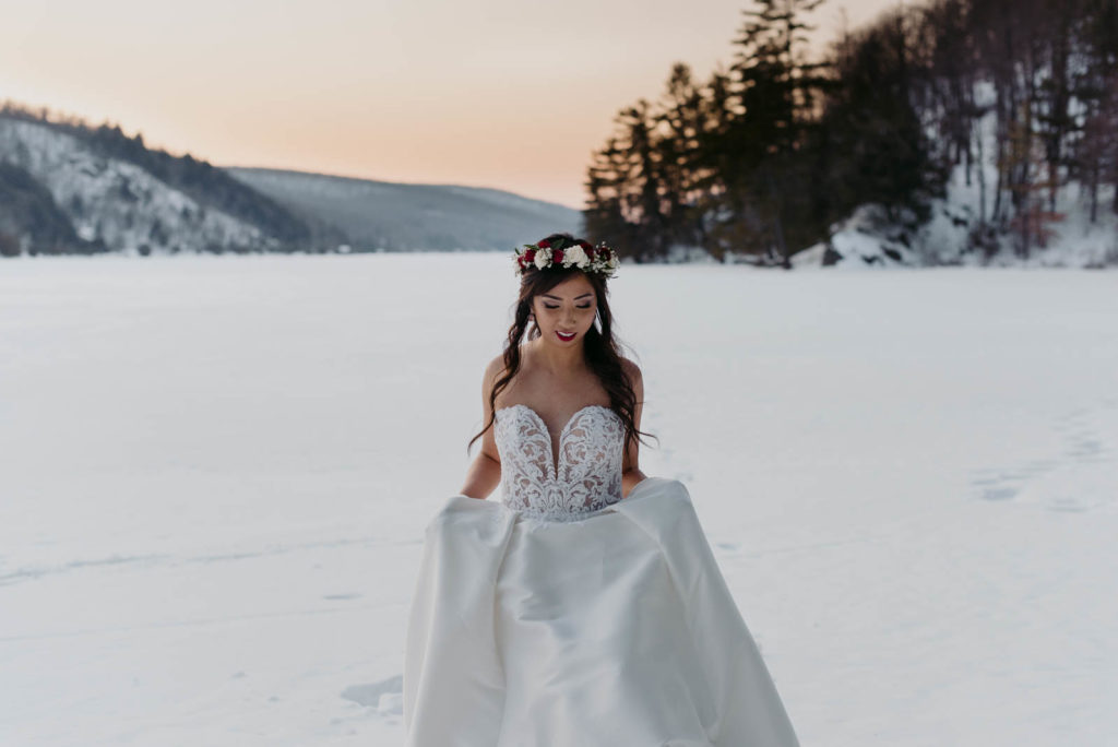 bride walking on frozen lake at sunset wearing floral crown