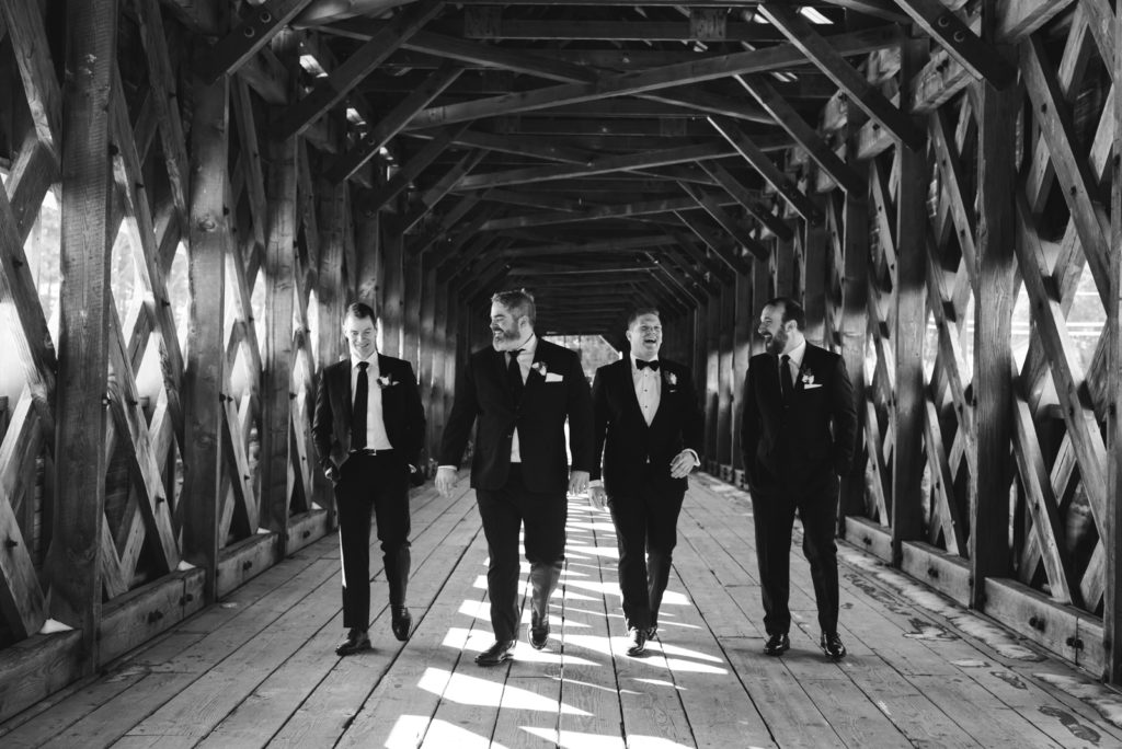 groomsmen walking along wakefield bridge in black and white