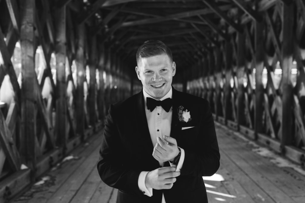 groom on wakefield bridge in black and white