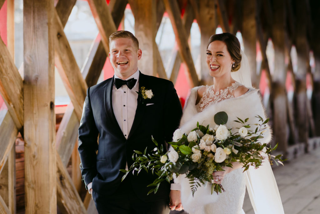 bride and groom holding hands smiling on the wakefield covered bridge