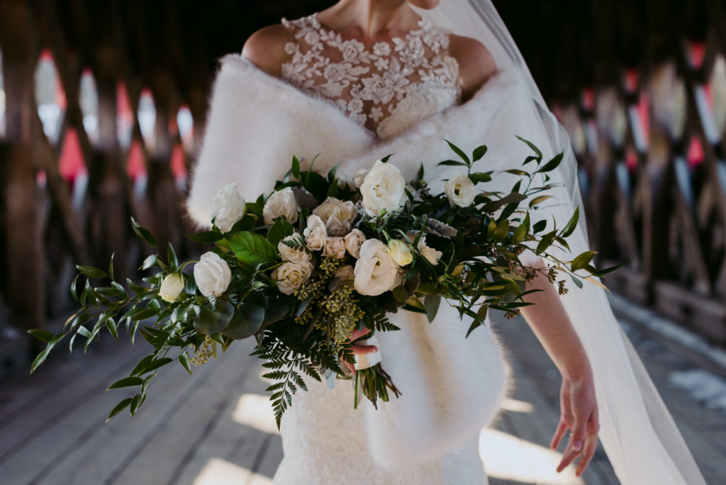 bride holding wedding bouquet with fur shall on wakefield bridge