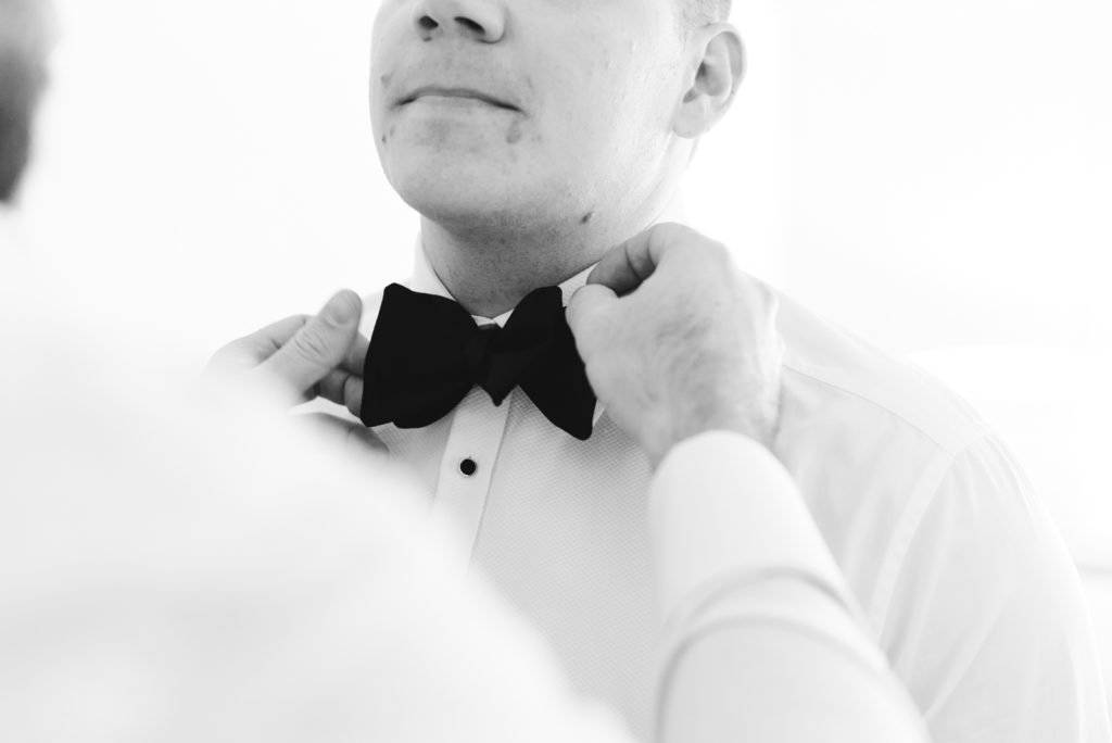 groomsman adjusting the groom's tie
