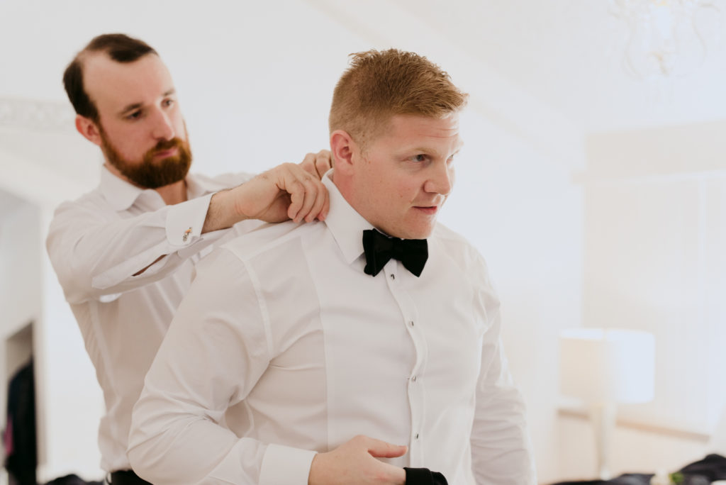 groomsman adjusting the groom's tie