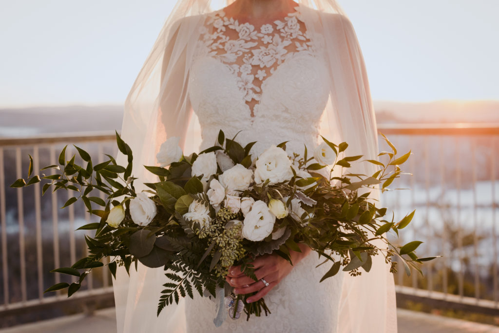 bride holding green and white bouquet at sunset at le belvedere