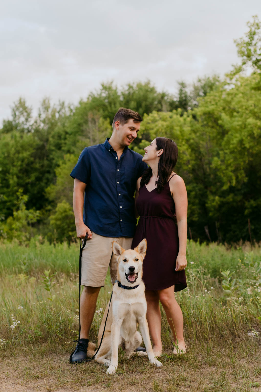 engaged couple in a field with their dog