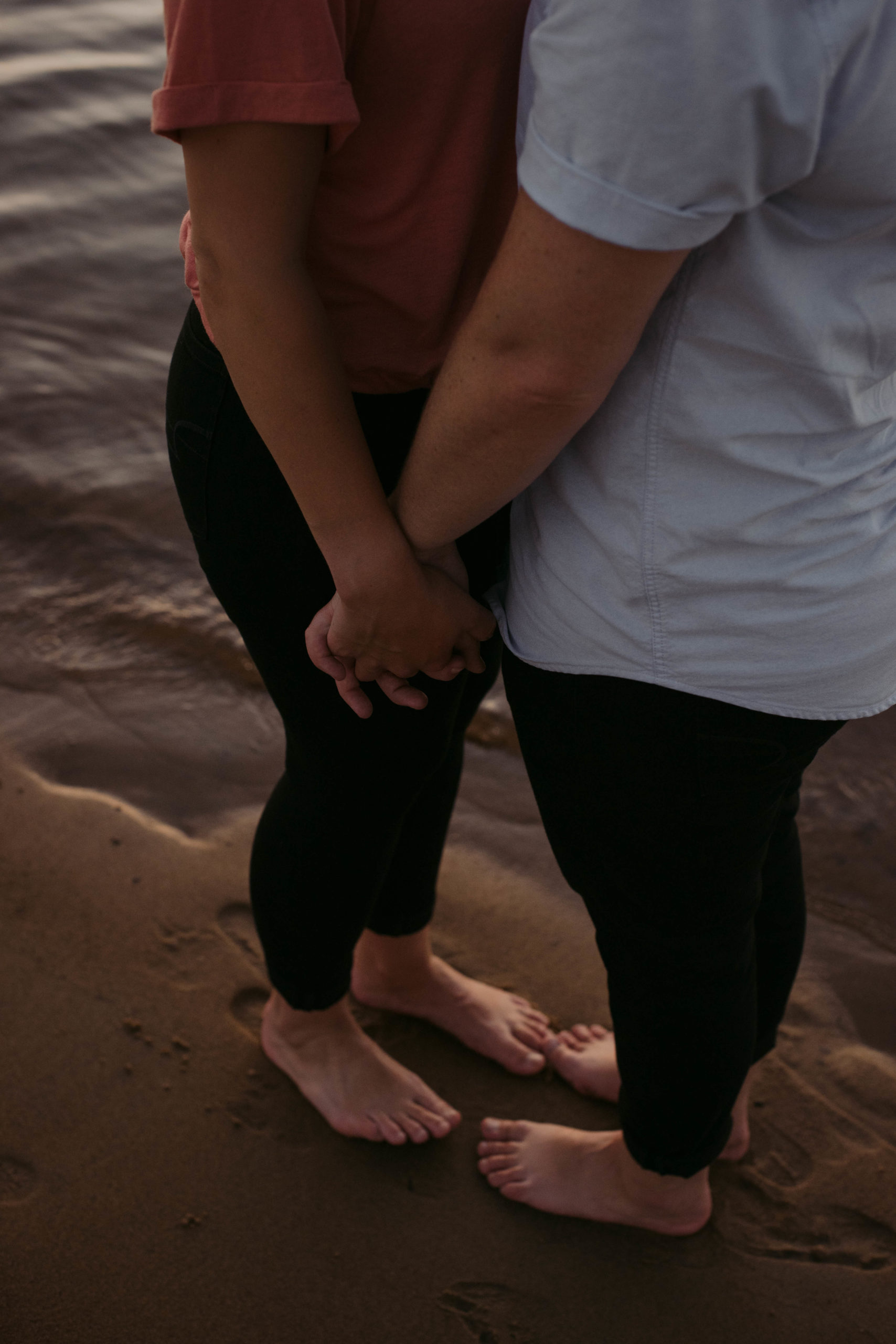 same sex couple holding hands by the water's edge