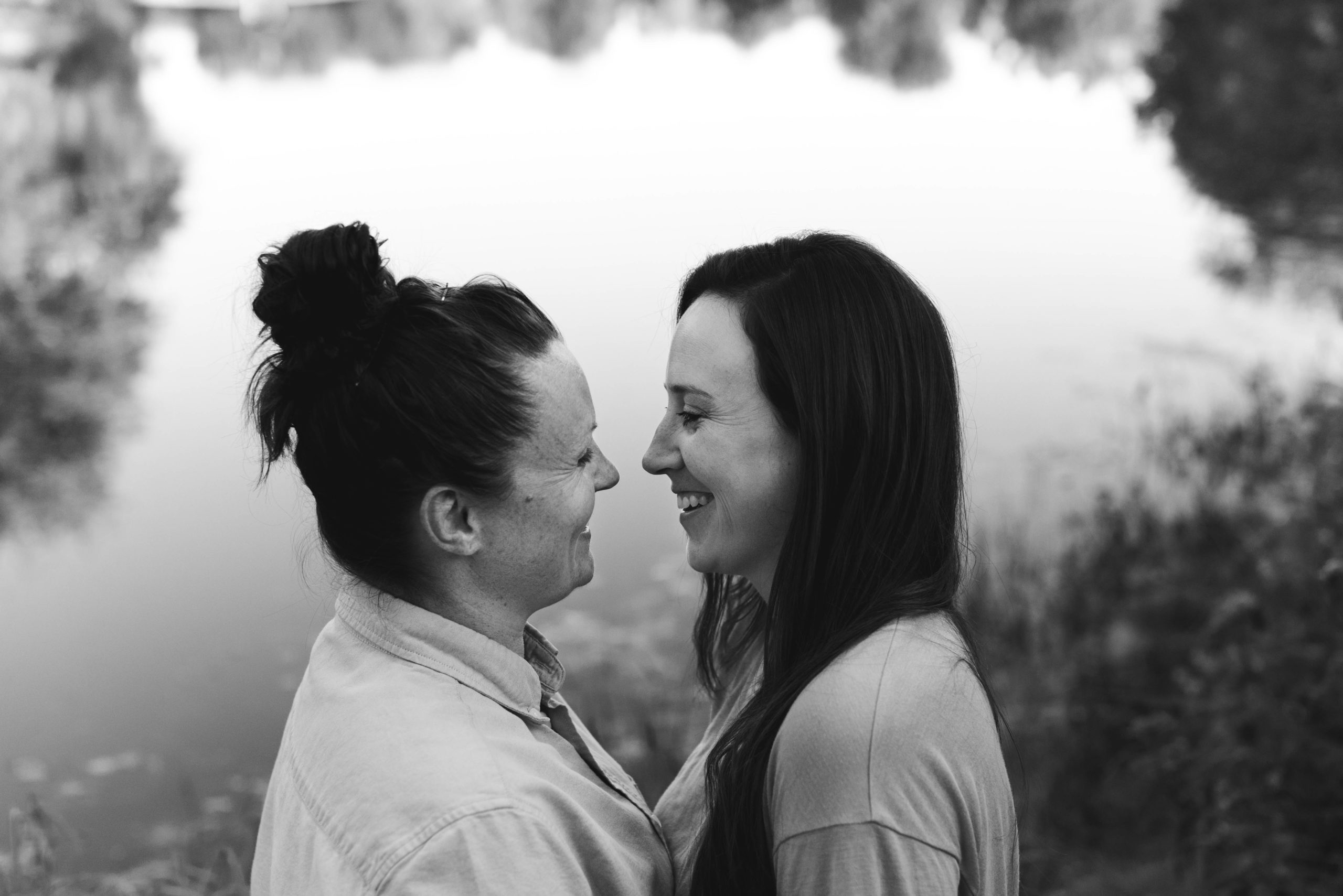 same sex couple laughing by the water in black and white