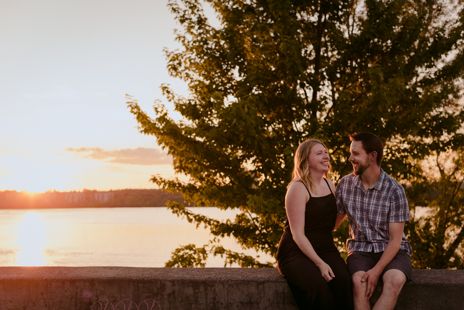 engaged couple sitting and laughing at sunset