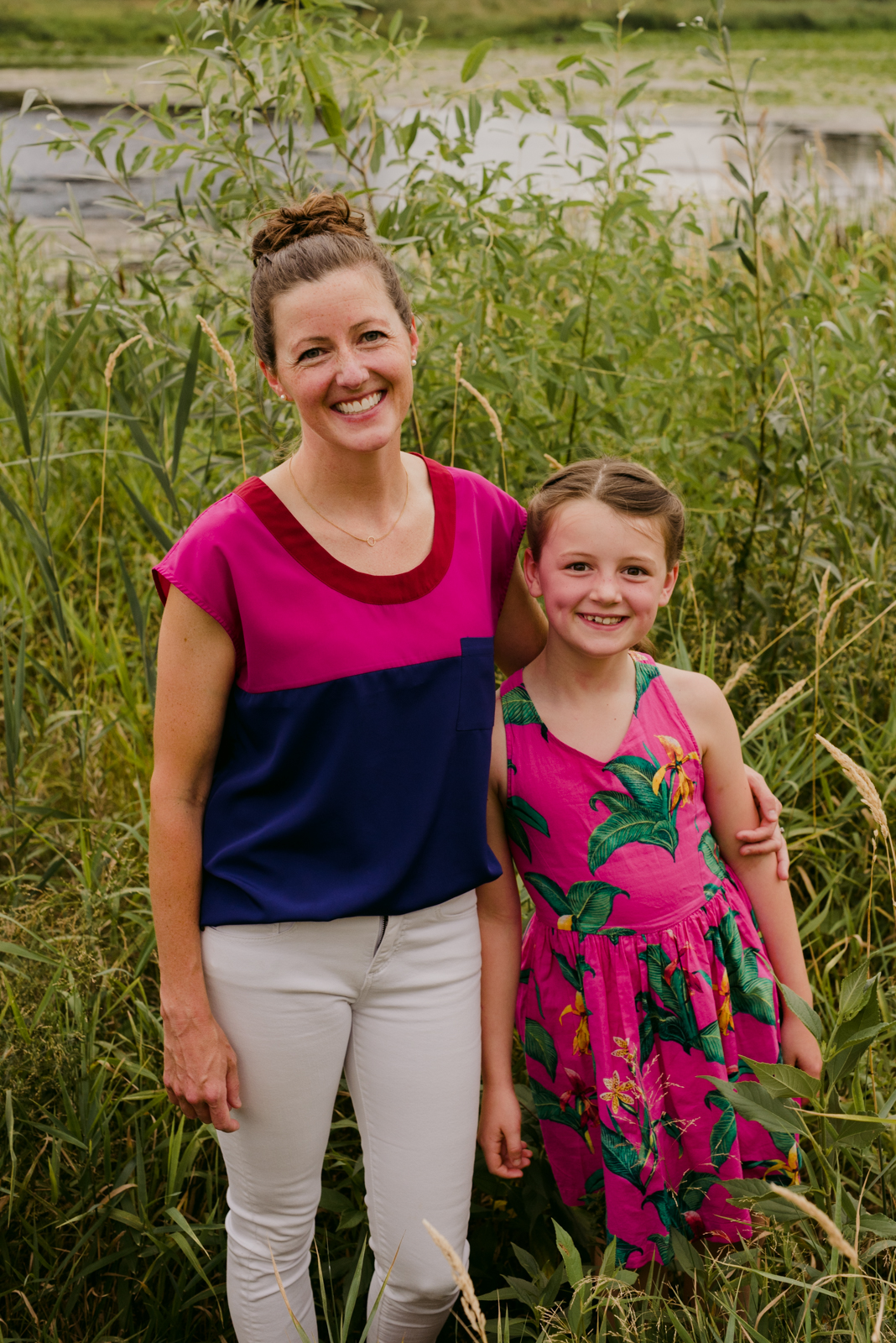 mom and daughter in pink standing in the long grass