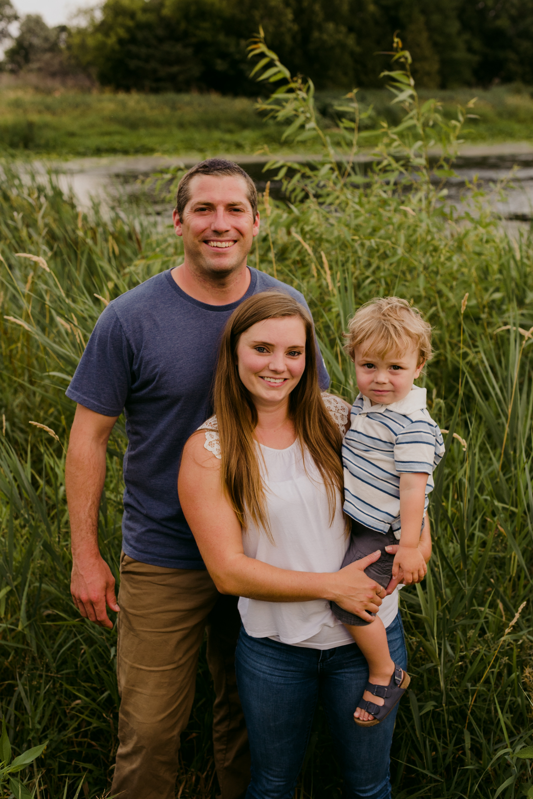 family smiling at the camera in tall grass