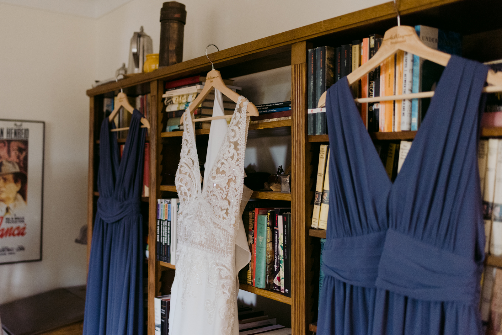 bride and bridesmaids dresses hanging from bookshelf
