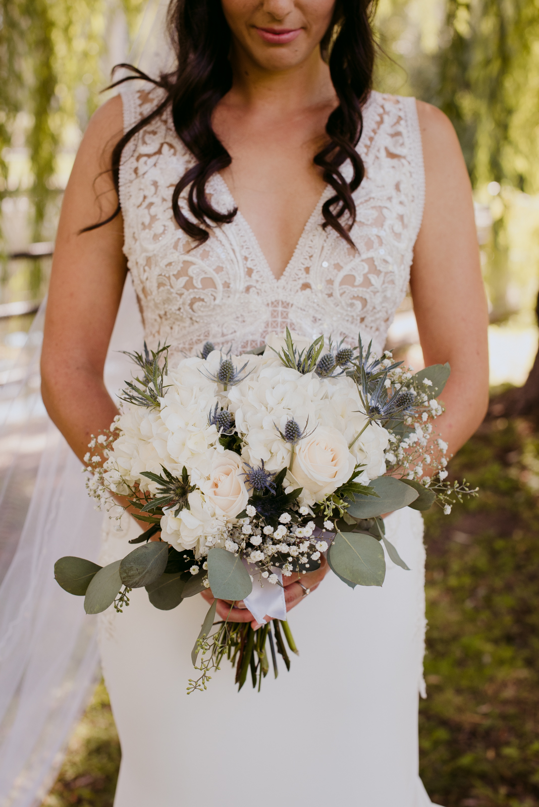 bride holding wedding bouquet in the willow trees by patterson's creek