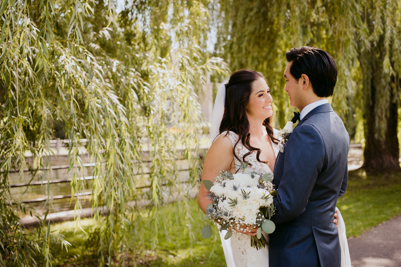 bride and groom smiling at each other by the willow trees by patterson's creek
