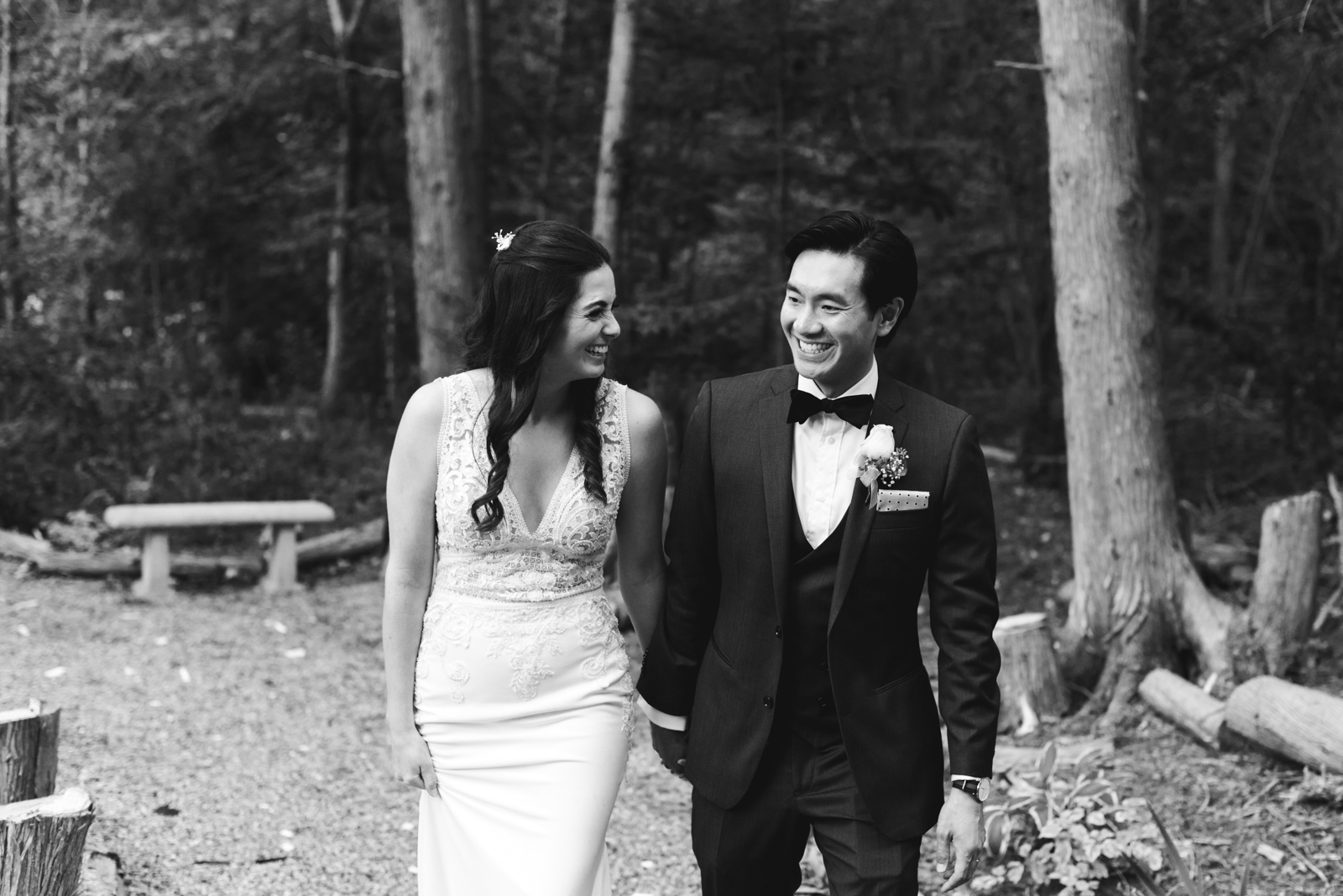 bride and groom holding hands walking through the forest laughing