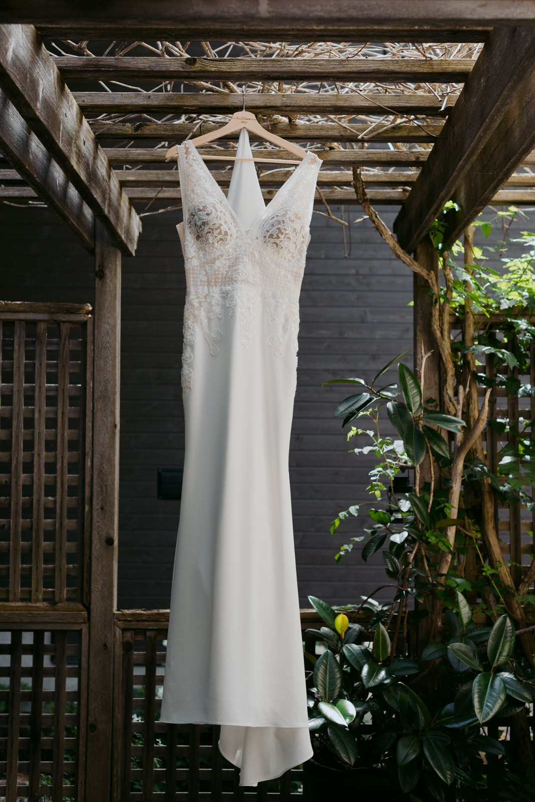 wedding dress hanging from pergola with plants