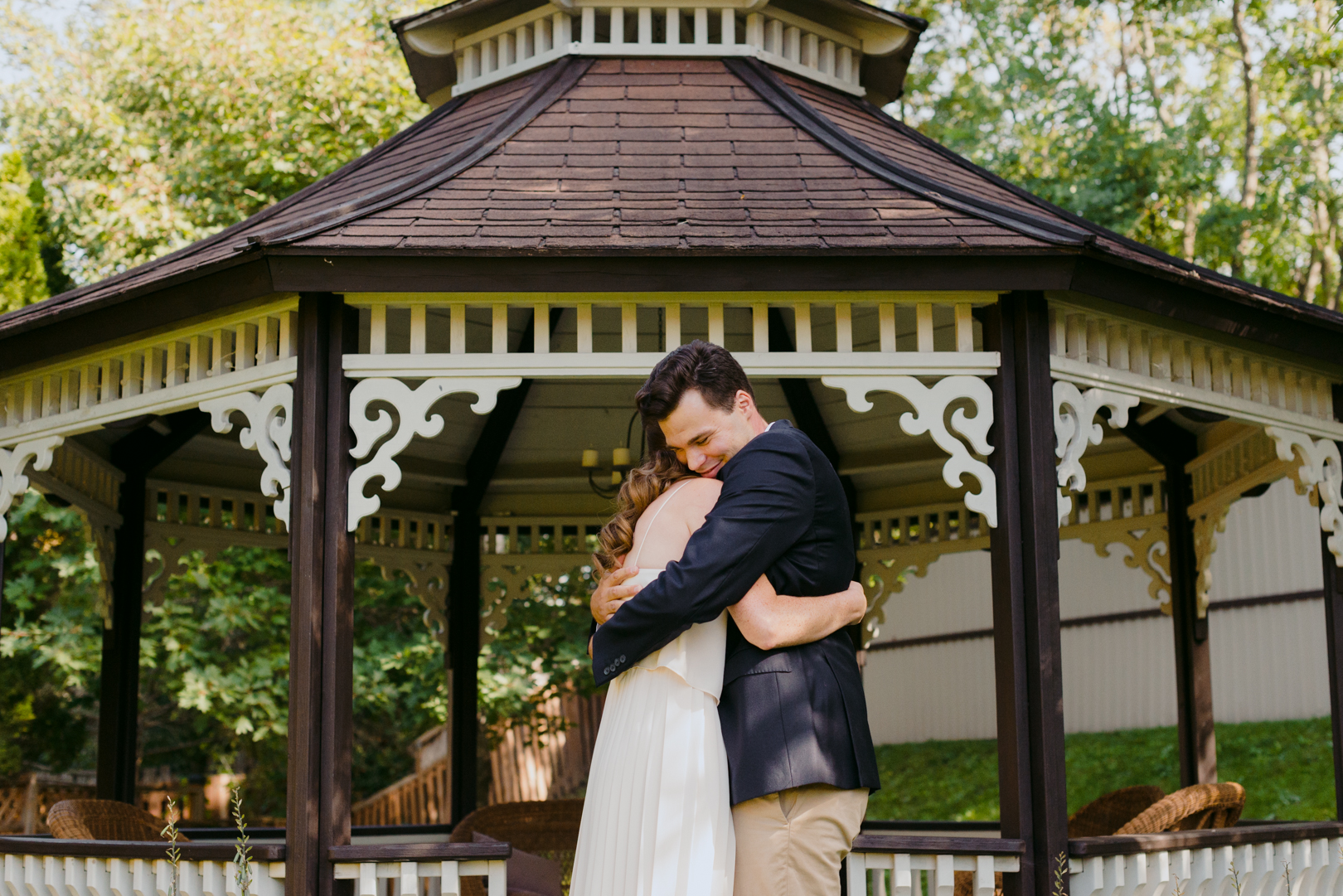 bride and groom hugging after wedding ceremony in front of pergola in backyard