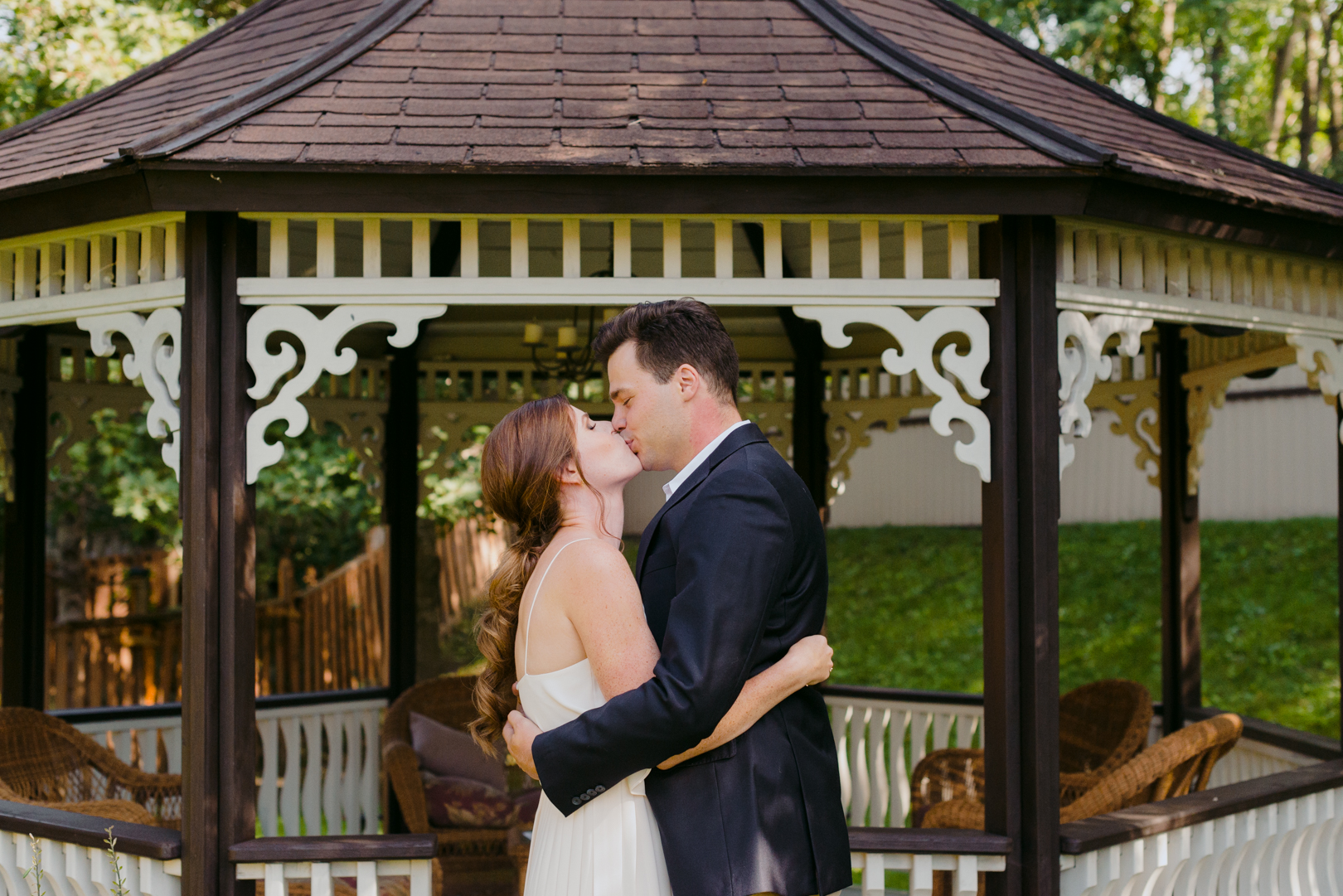 bride and groom first kiss in front of pergola during backyard wedding ceremony