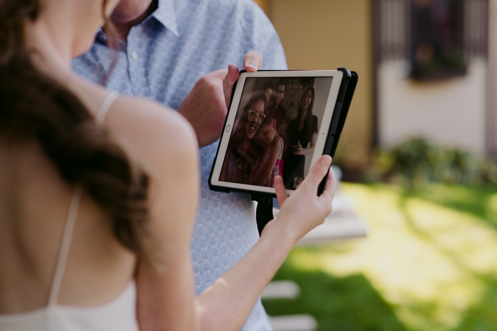 bride looking at her family who are live streaming the wedding ceremony on the ipad