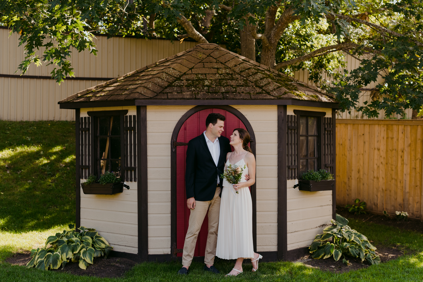 bride and groom in front of red shed door in backyard