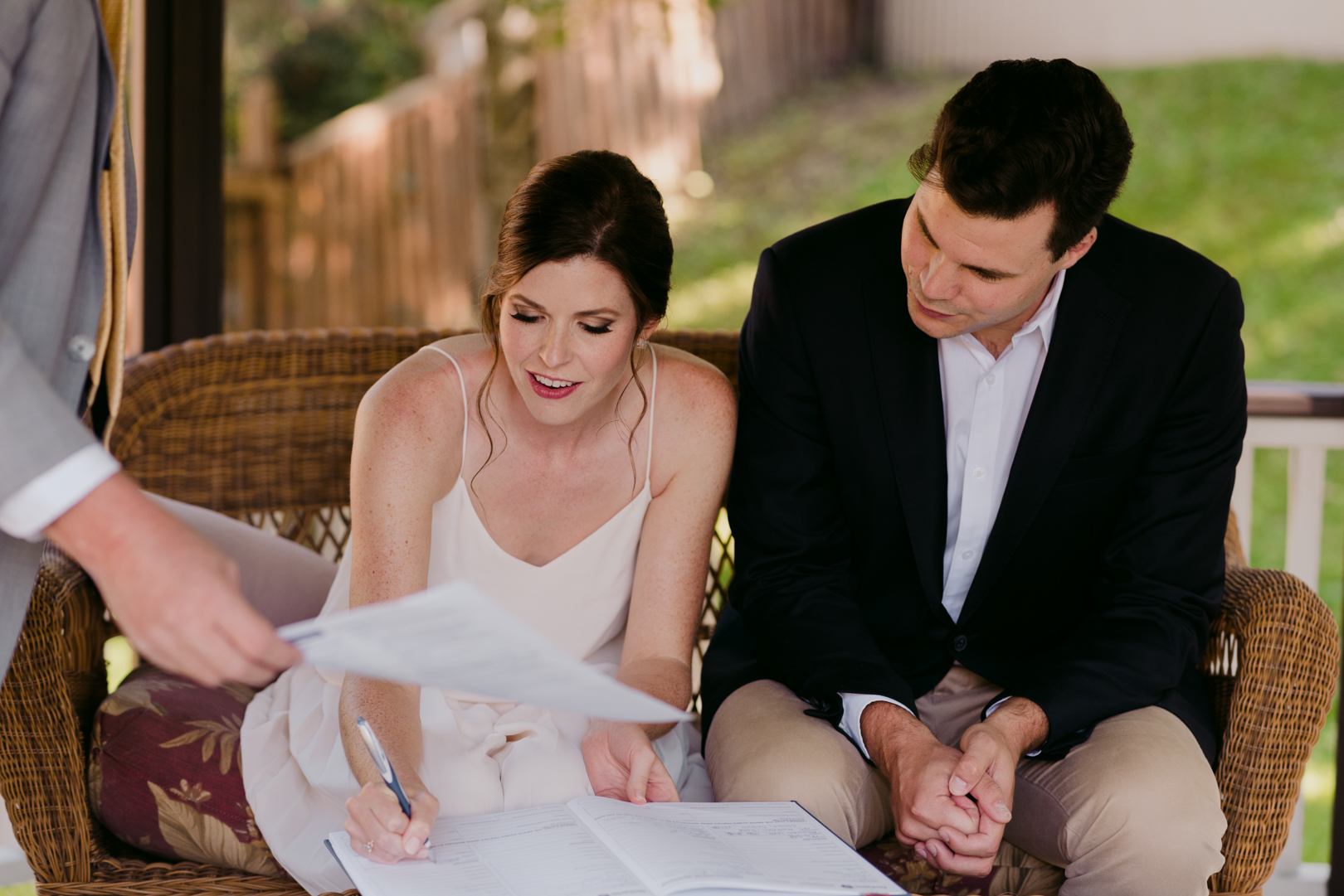 bride and groom signing marriage license during backyard wedding ceremony