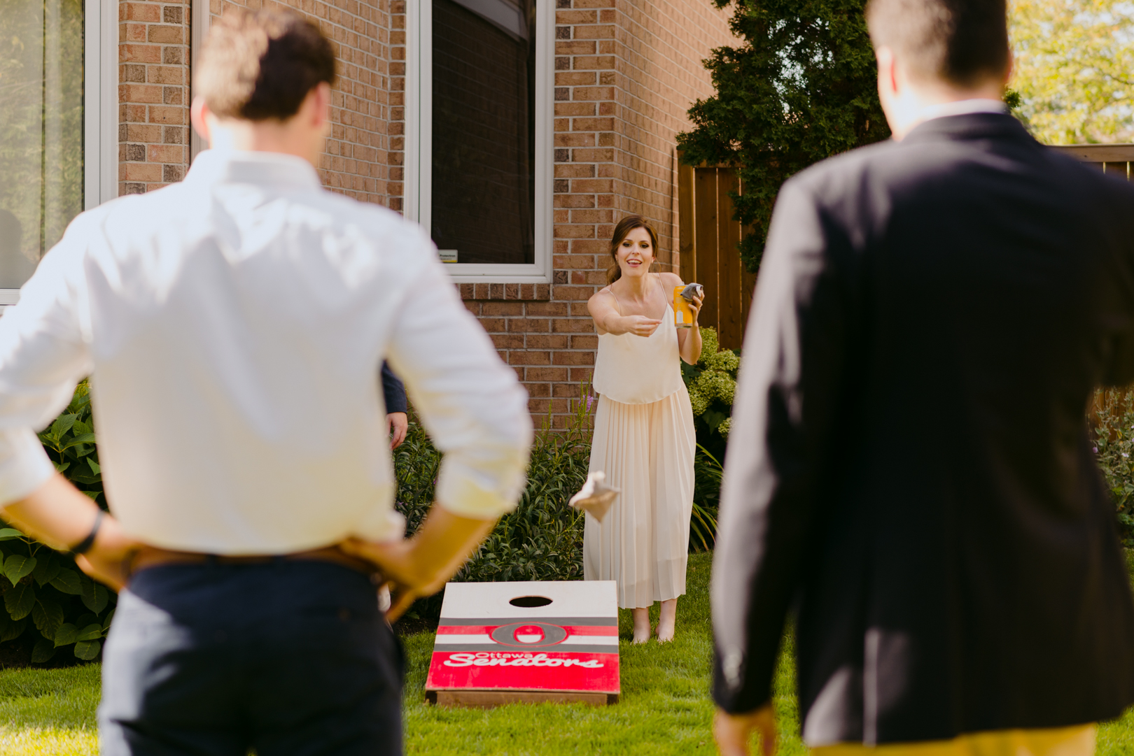 bride holding a beer playing backyard lawn games