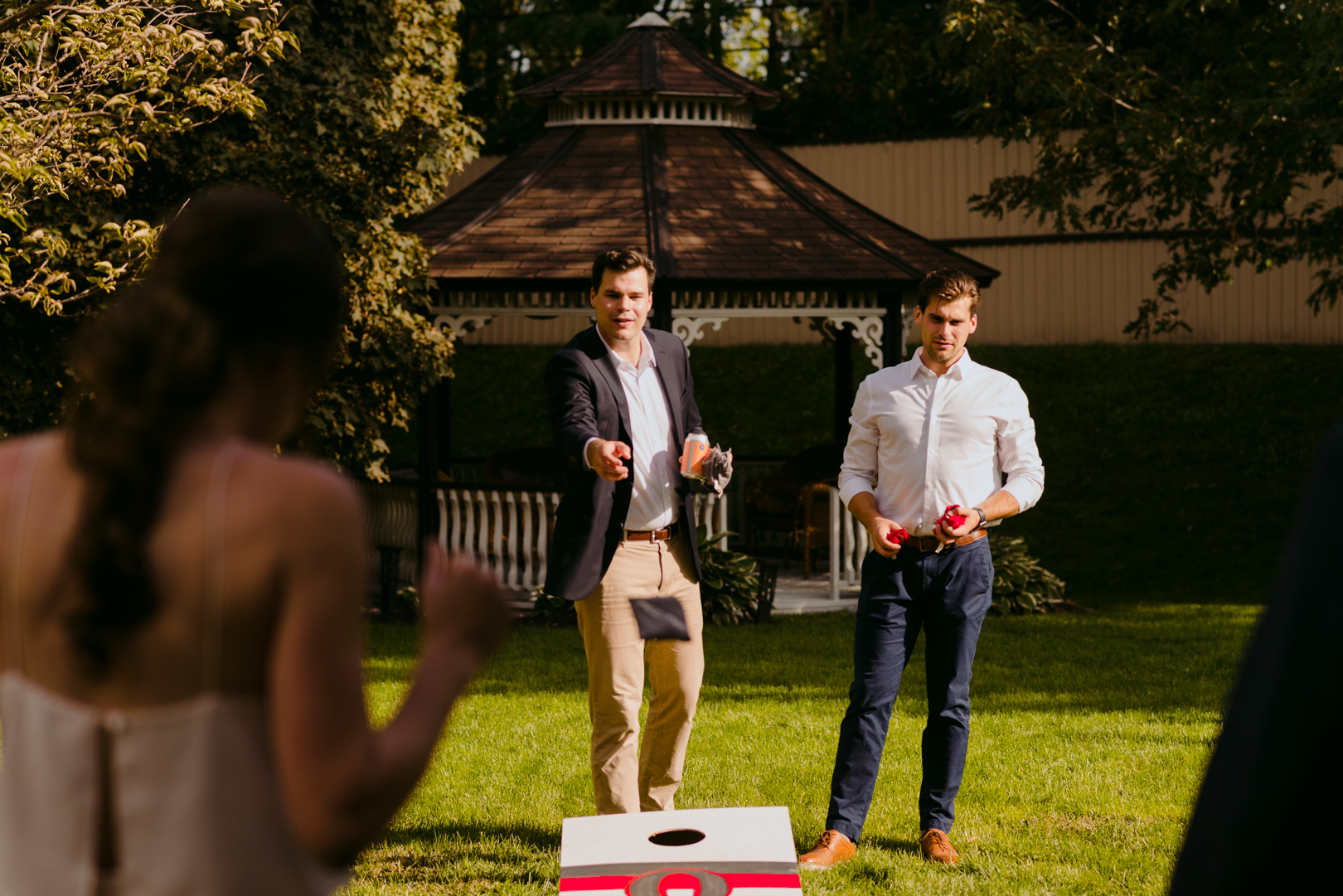 groom and brother playing lawn games during backyard wedding