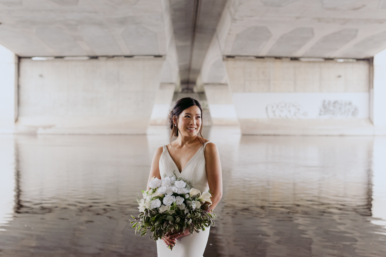 bride underneath a bridge holding wedding bouquet