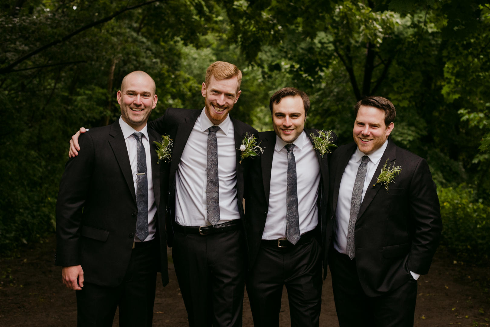 groom and groomsmen laughing and smiling at the camera in a forest